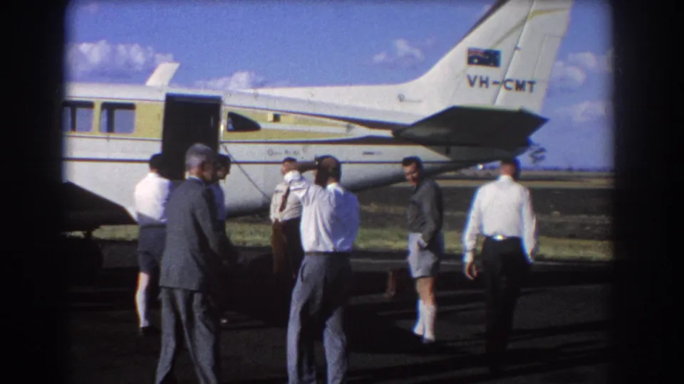 In Brisbane, Australia in 1967, several men gather beside an open white-and-yellow aircraft marked VH-CMT.