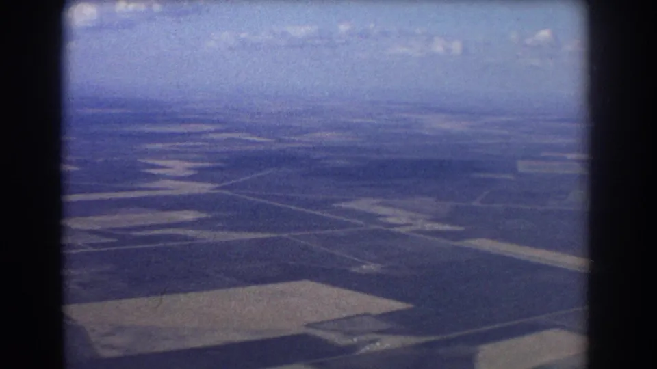 1967 Brisbane-area home-movie frame showing farmland, roads, and distant horizon from a small aircraft.