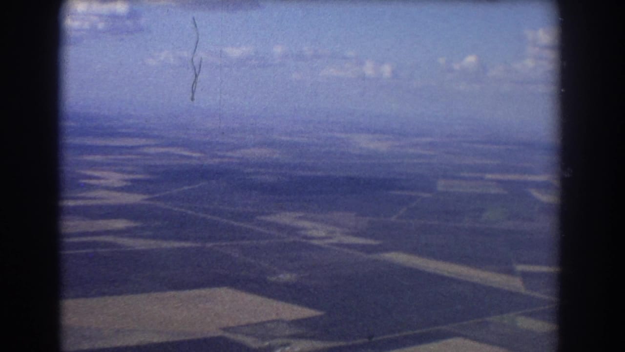 Aerial farmland landscape with fields and horizon under blue sky.