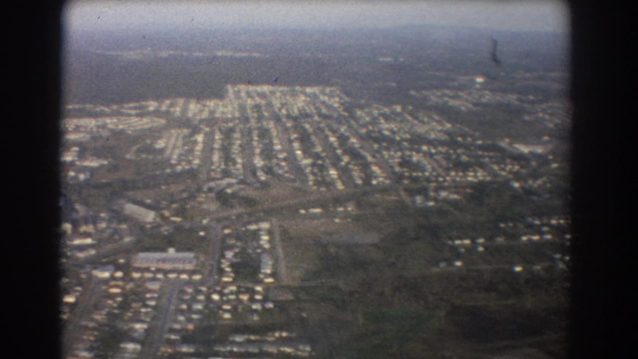 Aerial view of suburban housing blocks seen through an airplane-window frame.