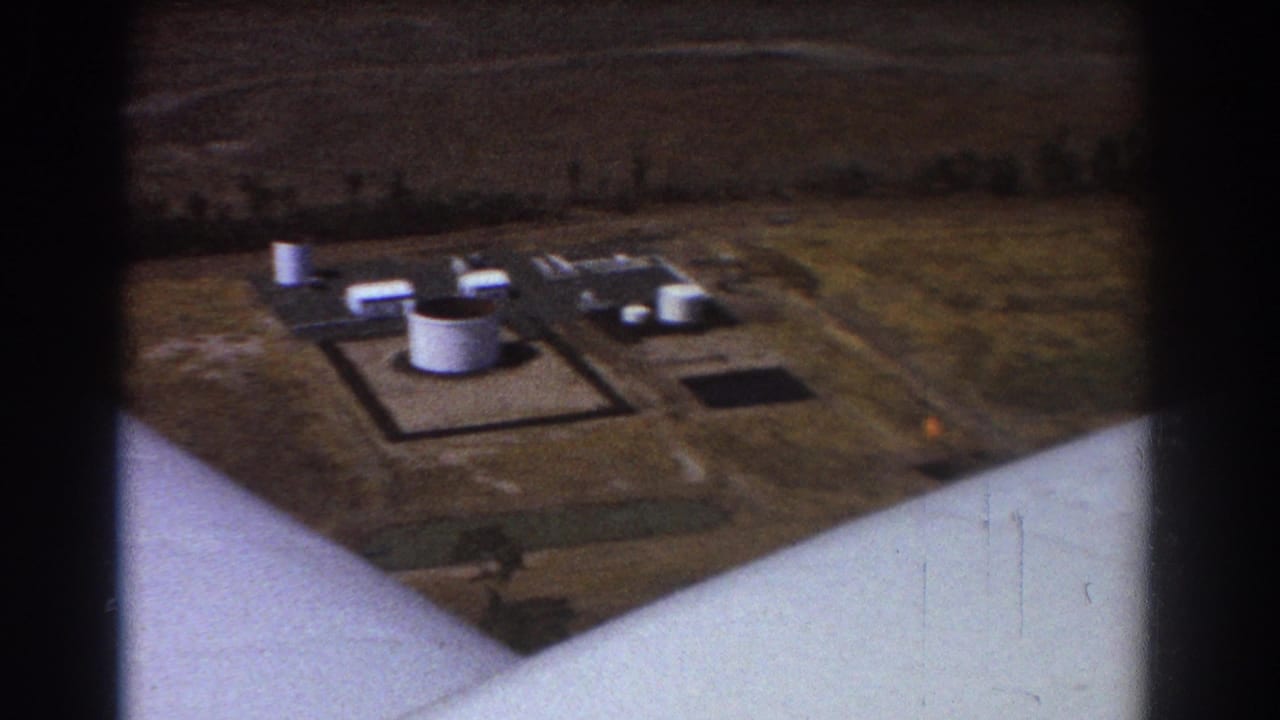 Industrial tanks and service buildings seen from an aircraft wing-side angle.