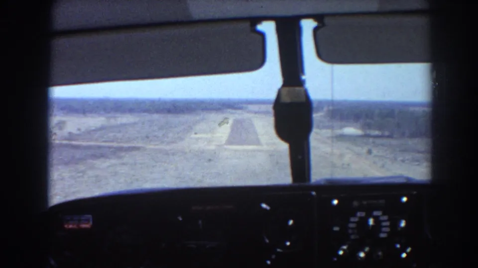 View through the aircraft cockpit toward a rural runway near Brisbane, with dashboard instruments silhouetted in the foreground.