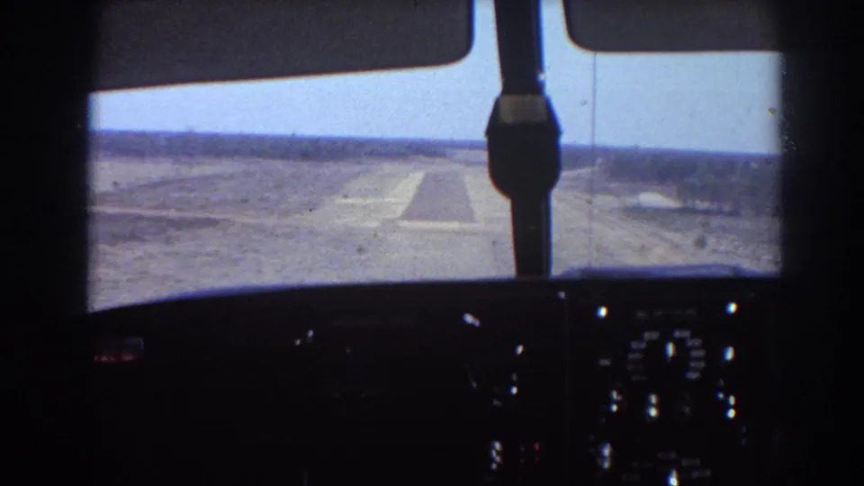 Cockpit perspective from a 1967 home-movie clip, with runway centered beyond the windshield and dark dashboard below.
