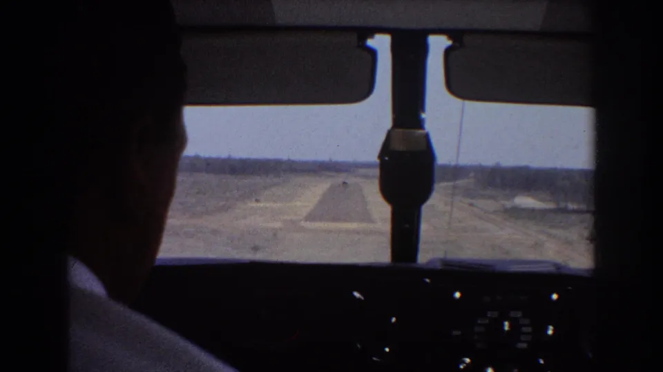 Late-frame cockpit view from 1967 footage showing the runway ahead and a dark, unidentifiable head silhouette near the right side.