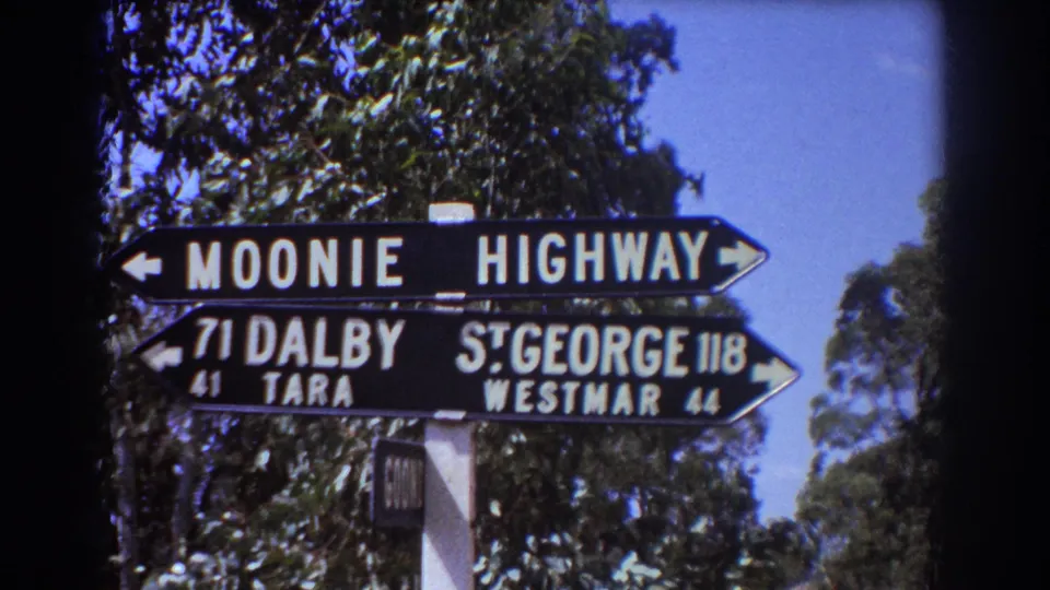 Soft 8mm frame of the Moonie Highway direction sign with Dalby, Tara, St. George, and Westmar distances visible.