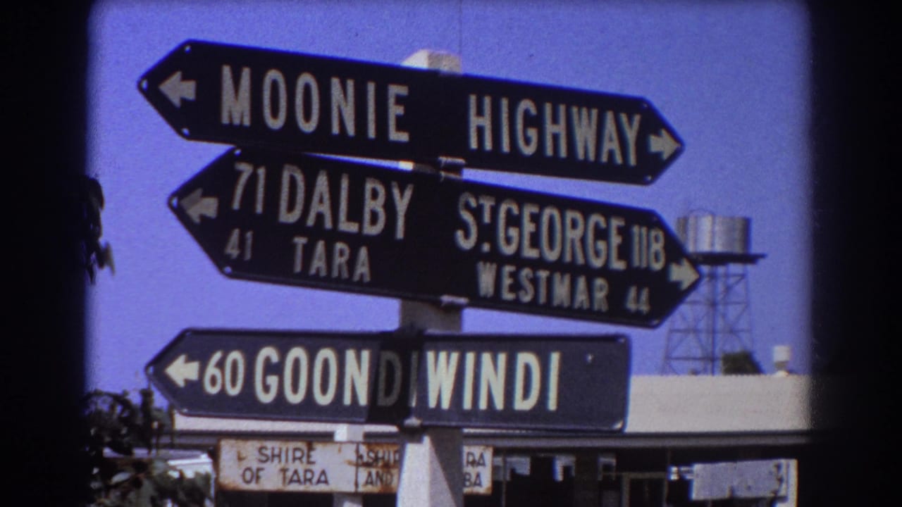 Black directional road signs with white lettering against a blue sky.
