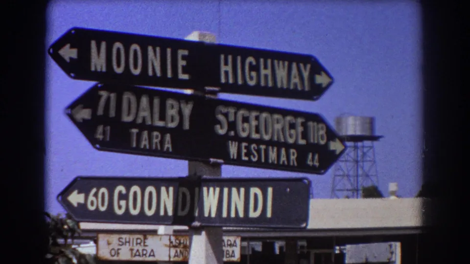 Handheld 8mm view of regional Queensland direction signs, with Goondiwindi, Dalby, Tara, St George, and Westmar visible.