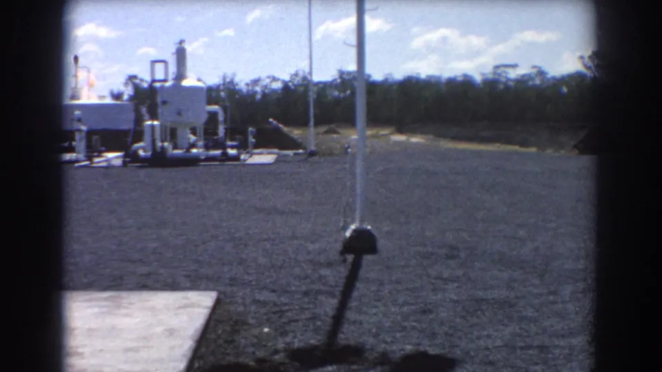 A wider 1967 Brisbane view shows industrial equipment, a pole and open paved ground with trees or scrub beyond the site.