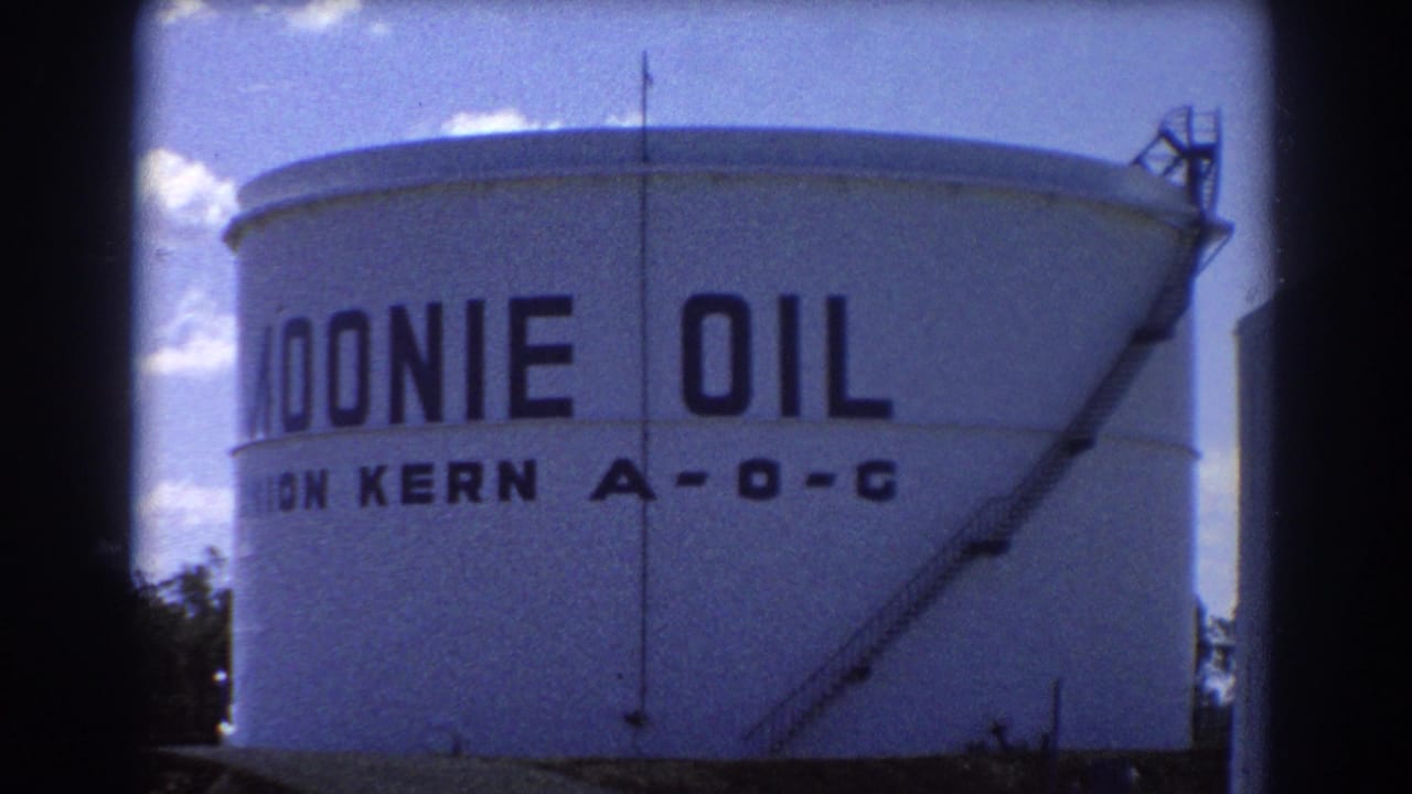 1967 Brisbane frame focused on a large white cylindrical tank marked MOONIE OIL and UNION KERN A-O-C under a bright blue sky.