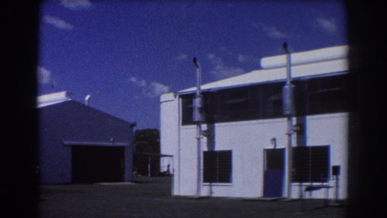 White industrial-style buildings under a deep blue sky beside a paved yard.