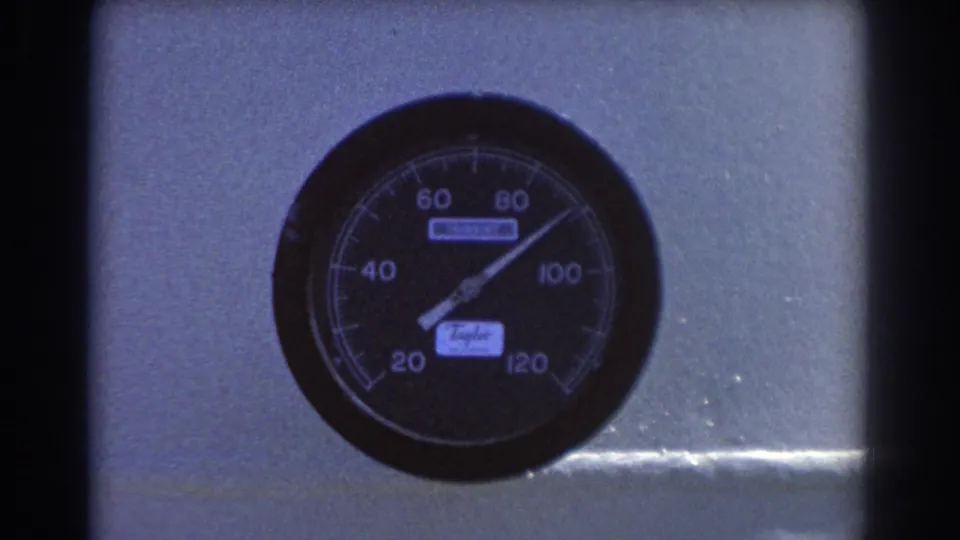 1967 8mm close-up of the same pressure gauge, showing the dial, needle, and surrounding metal panel.
