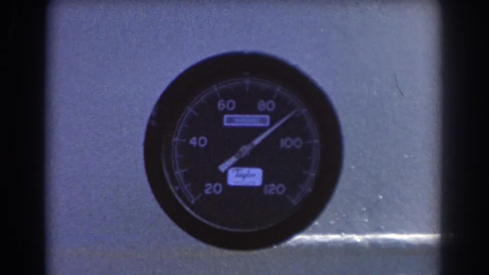 Close-up of the Taylor pressure gauge in Brisbane 1967 footage, with dark 8mm frame edges around the metal panel.