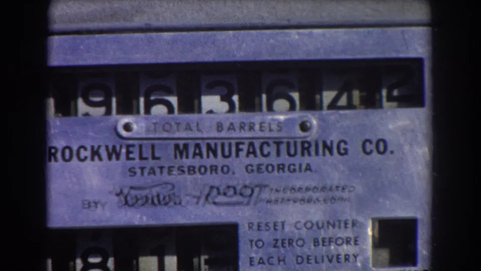 1967 Brisbane home-movie close-up of the Rockwell TOTAL BARRELS counter, with visible numerals, reset instructions, and film-frame borders.