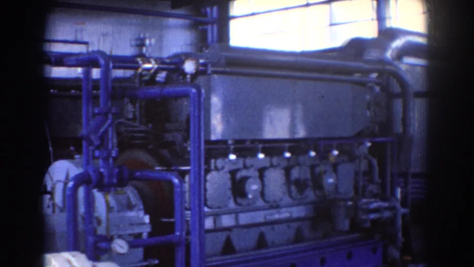 Brisbane 1967 industrial machinery view with blue pipework, gauges, large equipment casing, and bright upper windows.