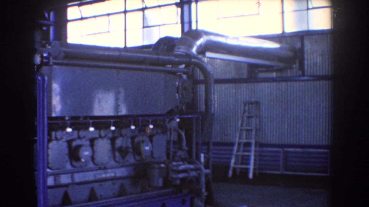 Industrial engine and blue pipework seen from a slightly shifted angle indoors.