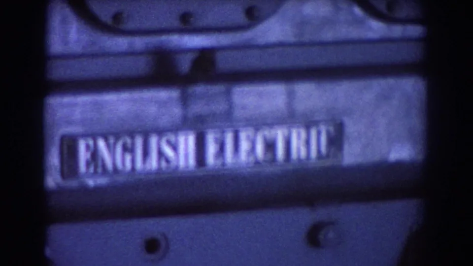 Close 8mm view of the engine body showing bolts, metal casing, and a readable English Electric label.