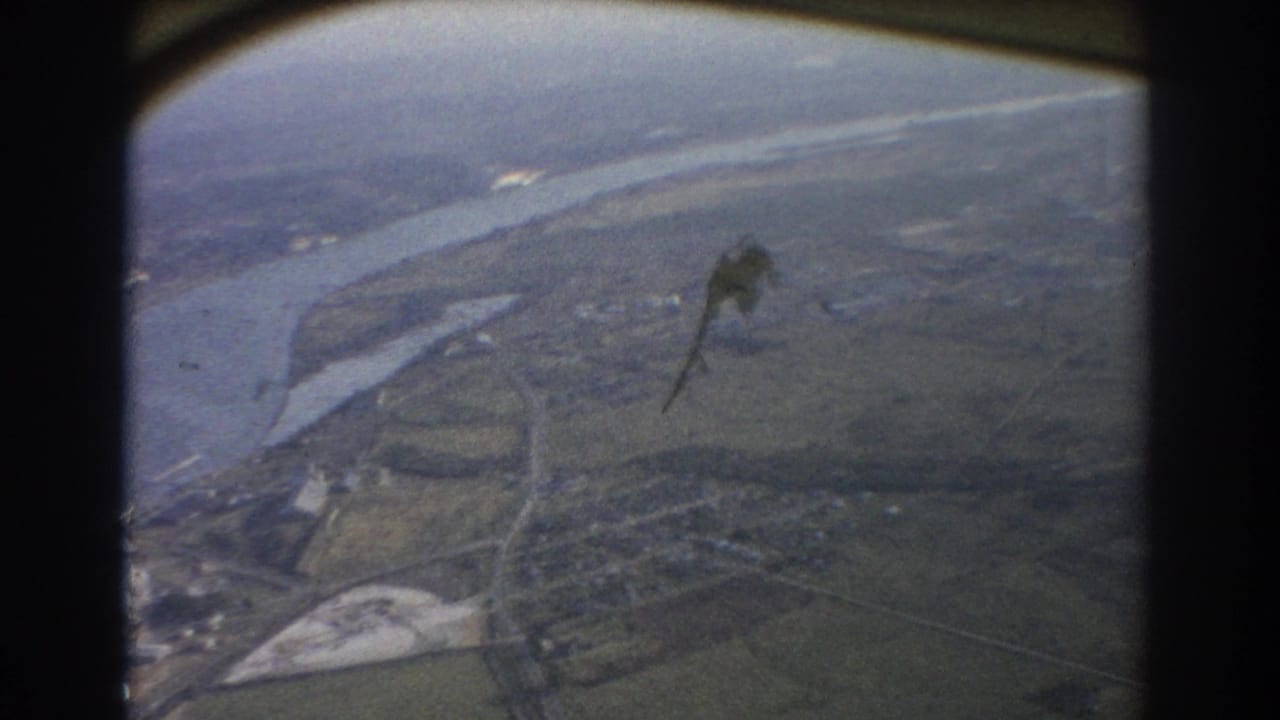 Aerial view over a winding river, fields, roads, and scattered buildings, with dark film-frame borders.