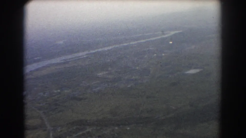 1967 Brisbane-area aerial frame with a river crossing the upper view, patchwork land below, and soft 8mm color fading.