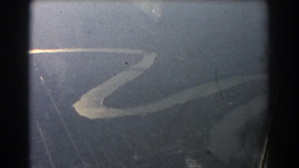 Final 1967 Brisbane-area aerial frame showing the winding river fading into hazy terrain through the plane window.