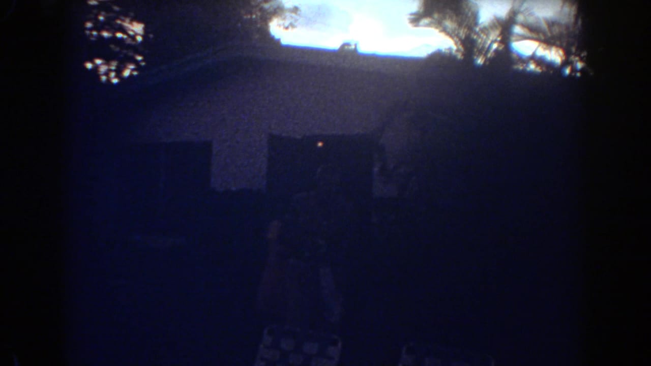 A blue-tinted 8mm frame shows the Fort Lauderdale house exterior at dusk, with a faint person near the doorway and a lawn chair below.
