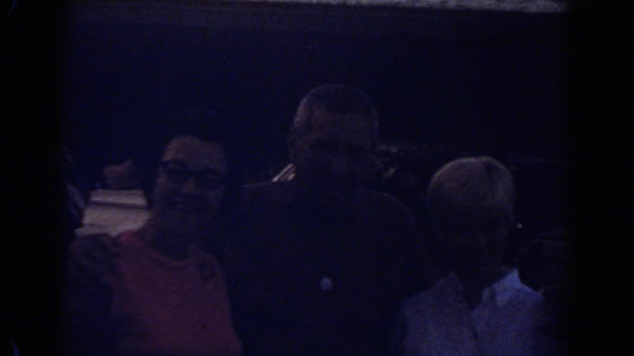 Underexposed home-movie view of a family group standing together in Fort Lauderdale, Florida, in 1967.
