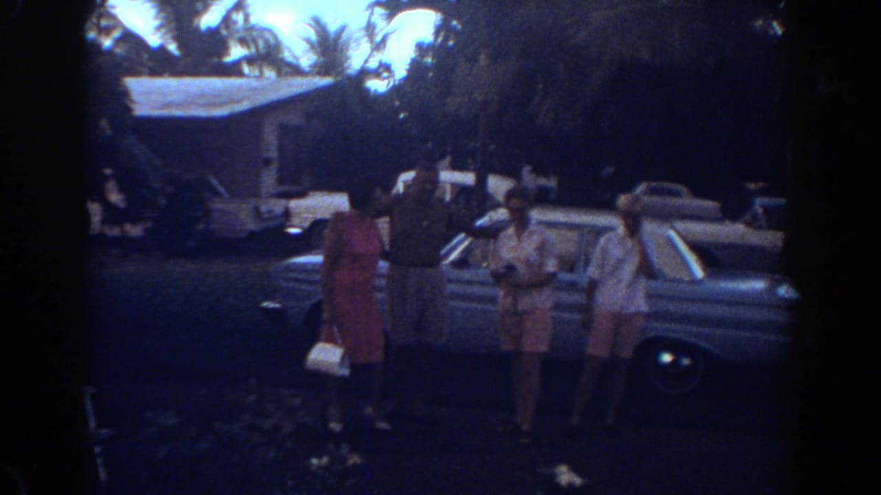Four family members pose beside a classic sedan in a palm-lined Fort Lauderdale residential setting in 1967.