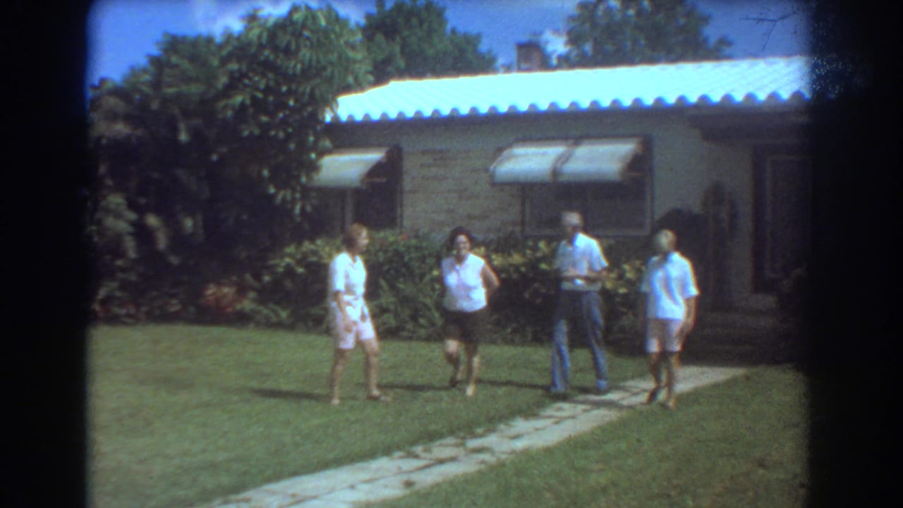 Four older adults outside a Fort Lauderdale brick ranch house in 1967, with lawn, walkway, awnings, and tropical shrubs visible.