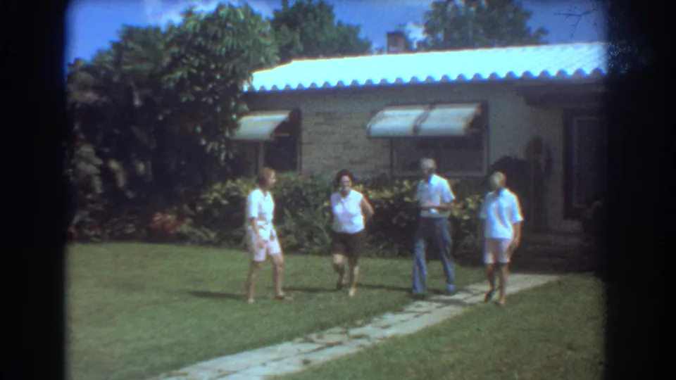 Four older adults outside a Fort Lauderdale brick ranch house in 1967, with lawn, walkway, awnings, and tropical shrubs visible.