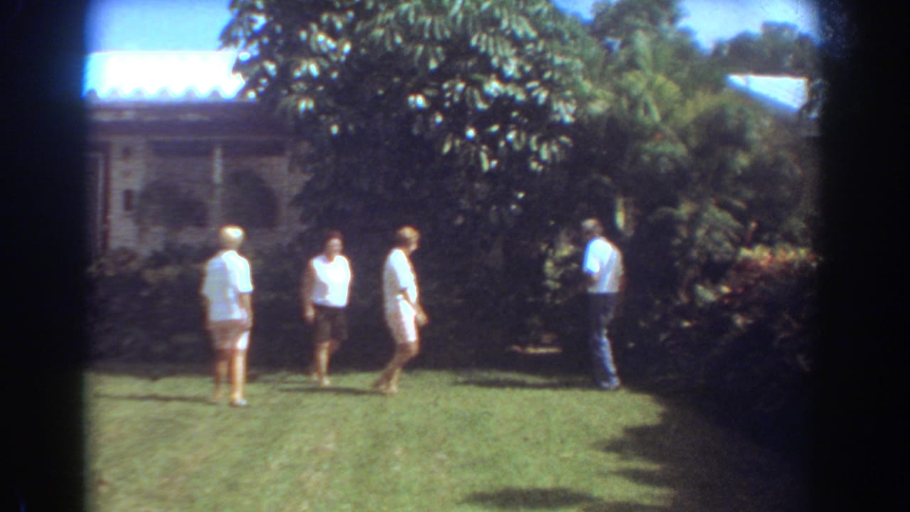 A small group of adults walks through a Fort Lauderdale residential yard, with tropical foliage and a house exterior in the background.