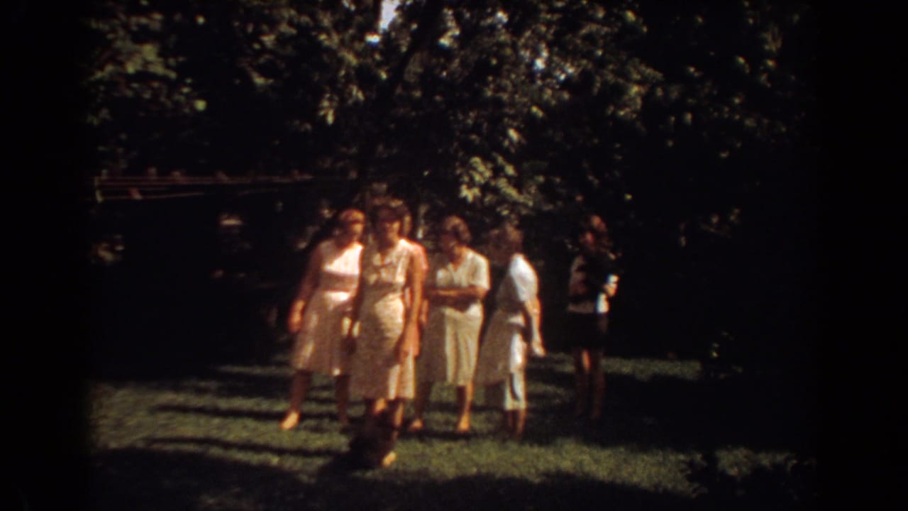 Women in light-colored dresses gather and move across a shaded Fort Lauderdale lawn in 1967 footage.