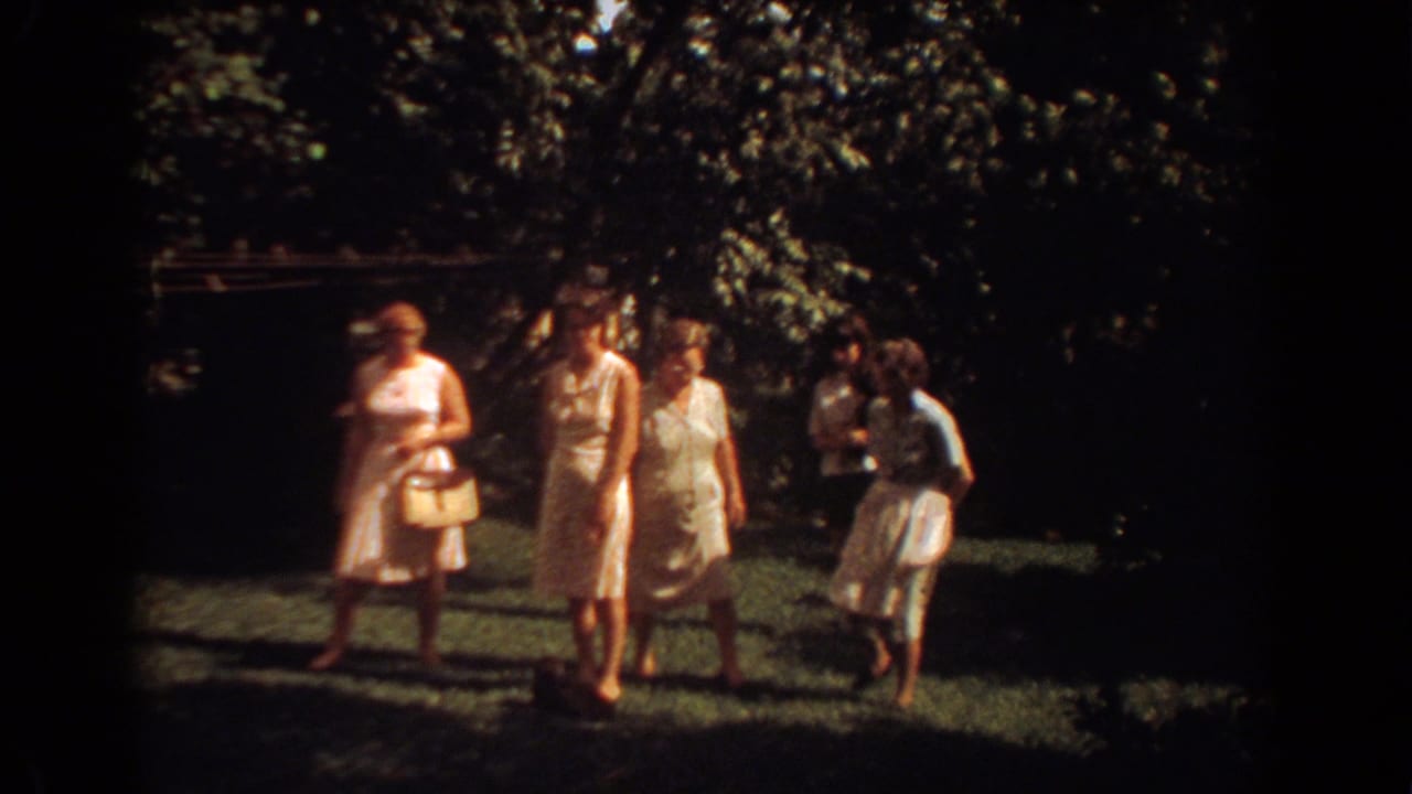 Women in summer dresses walk together on a shaded lawn in Fort Lauderdale, captured on 8mm film in 1967.