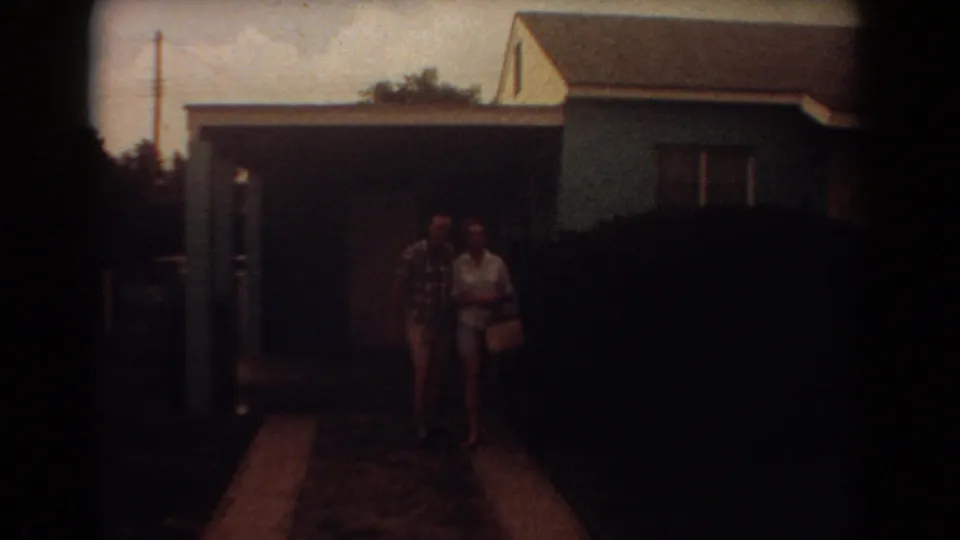 In Fort Lauderdale 1967 home-movie footage, an adult couple stands near a driveway before a blue house and large shrub.