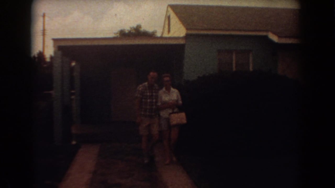 The couple walks arm-in-arm toward the camera outside a blue Fort Lauderdale house in 1967 home-movie footage.