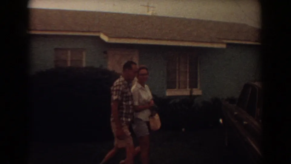 In 1967 Fort Lauderdale home-movie footage, a couple walks past a light blue house toward parked cars in the yard.