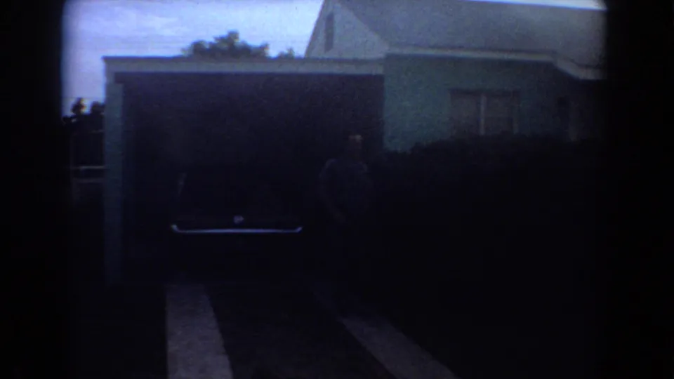 The final frame holds on a shadowed driveway and garage area outside the 1967 Fort Lauderdale house.