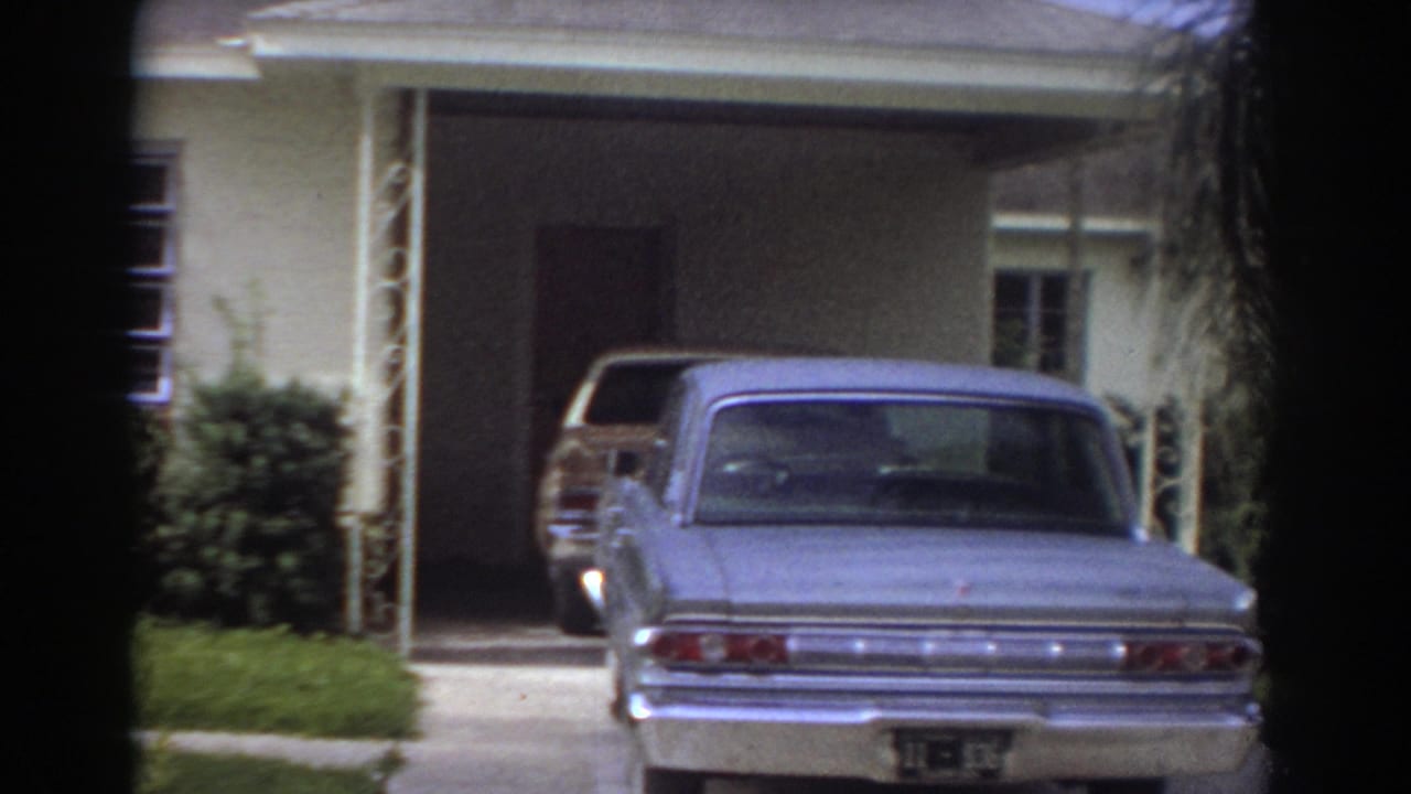 Driveway and garage area with a parked sedan beside a single-story house.