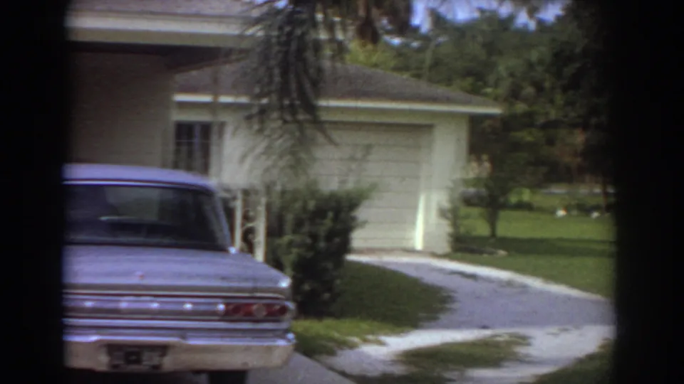 Fort Lauderdale 1967 home-movie view of a sedan near a garage, with lawn and trees around the driveway.