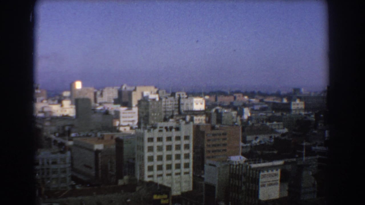 Elevated view across city buildings under a hazy blue sky.