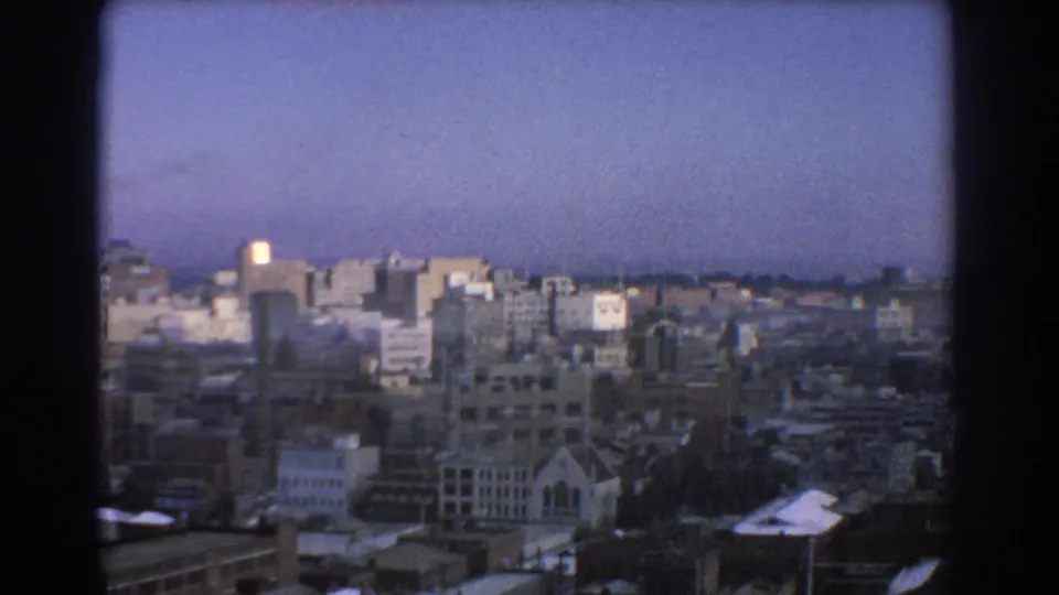 1967 Melbourne city panorama with older rooftops, taller commercial buildings, and a church-like spire visible near the lower center.