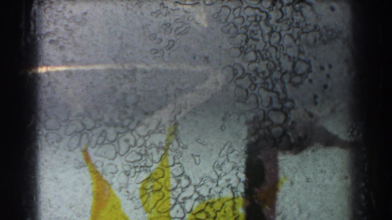 Damaged film frame with partial yellow artwork and dark frame borders.