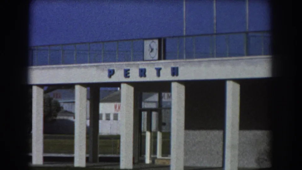 1967 Perth footage shows the facility entrance held in frame, with PERTH lettering, white columns, and visible 8mm film edges.