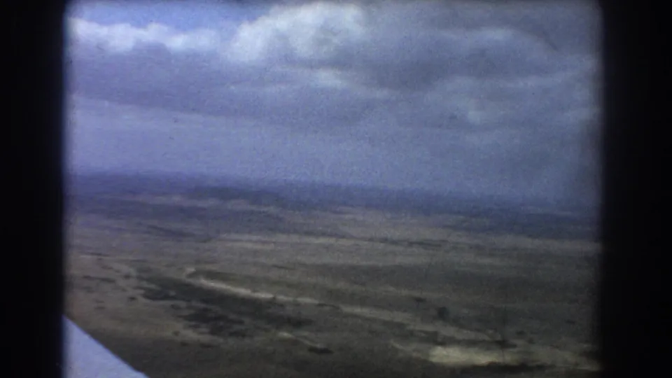 1967 Perth, Australia home-movie frame looking from an aircraft toward clouds and a wide, flat landscape below.
