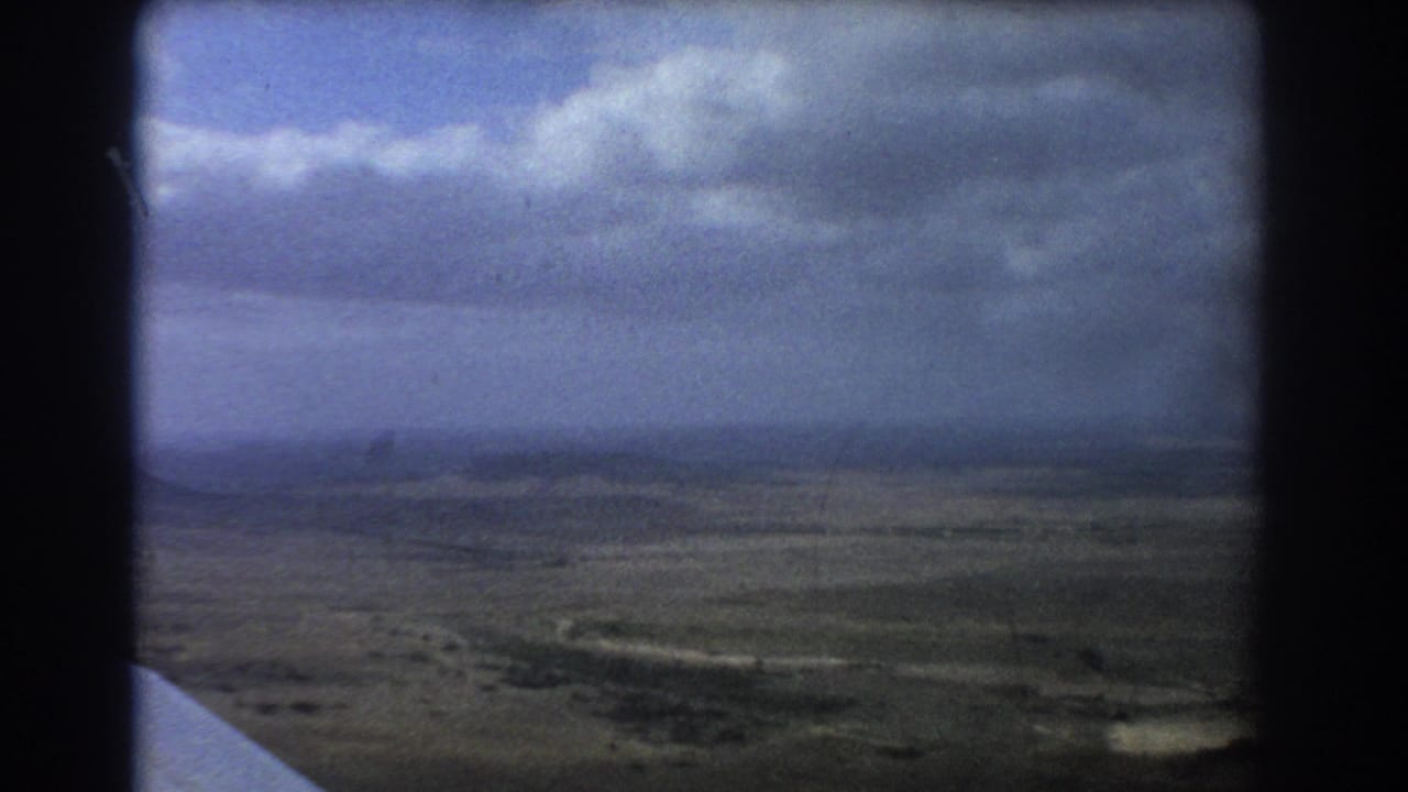 Aerial view of open land and cloud layers from an airplane window.