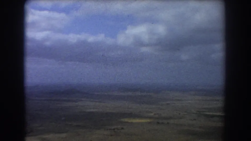 1967 8mm passenger view near Perth, Australia, looking through aircraft framing toward clouds and dry open land.