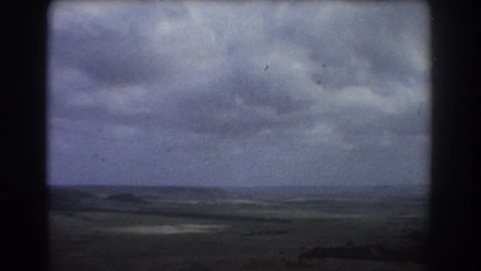 1967 Perth-area home-movie frame showing a cloudy sky over a broad, dark, distant landscape and low horizon.