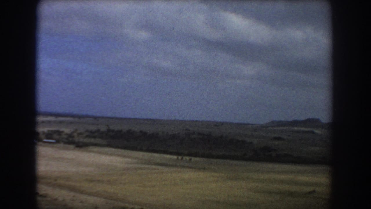 1967 home-movie aerial view near Perth showing open arid terrain, distant hills, and dark 8mm frame edges.
