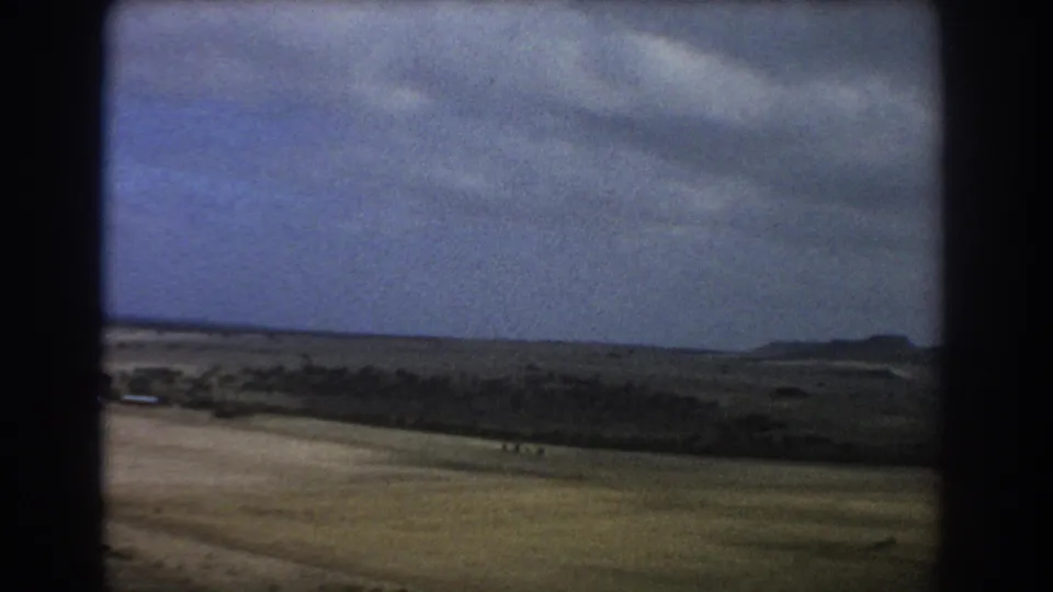 1967 home-movie aerial view near Perth showing open arid terrain, distant hills, and dark 8mm frame edges.