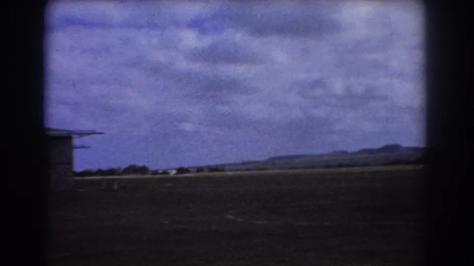 1967 Perth frame looking across an empty airfield toward a low horizon and hills, with the aircraft mostly out of view.