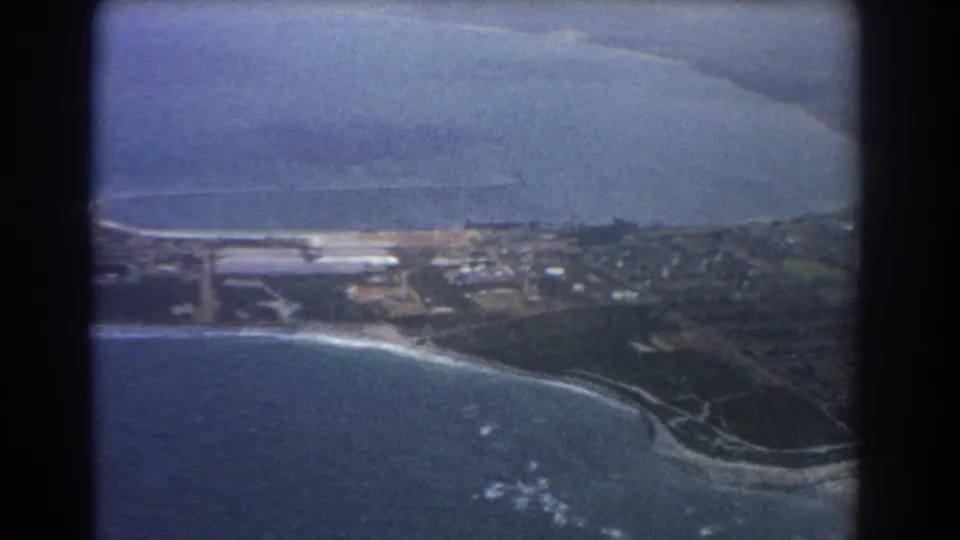 1967 Perth, Australia aerial view showing blue ocean, a curving beach, developed shoreline, buildings, roads, and a dark inlet.
