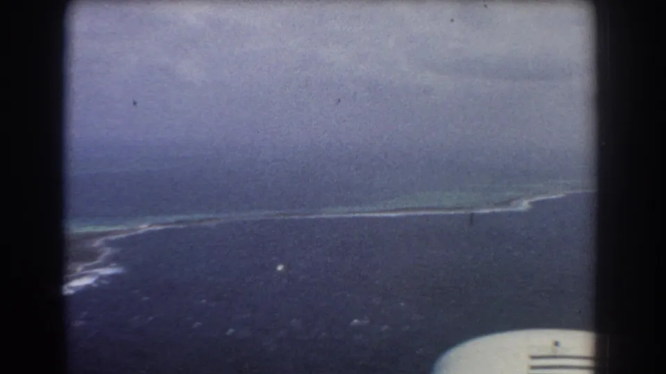 1967 8mm aerial view near Perth, Australia, showing a long reef or sandbar line and a partial aircraft-window foreground.